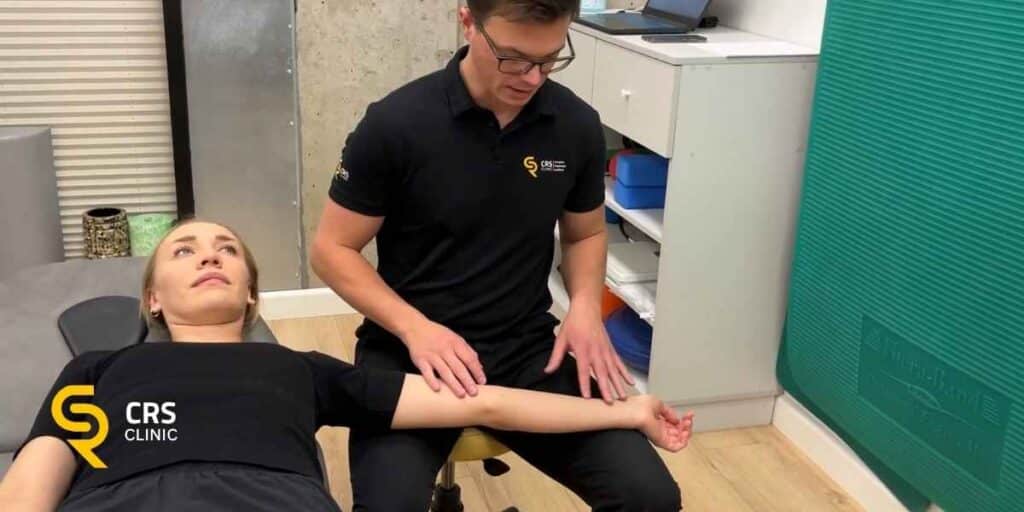 Fizjoterapeuta wykonuje z pacjentką z zespołem cieśni nadgarstka ćwiczenia neuromobilizacji w CRS Clinic Warszawa