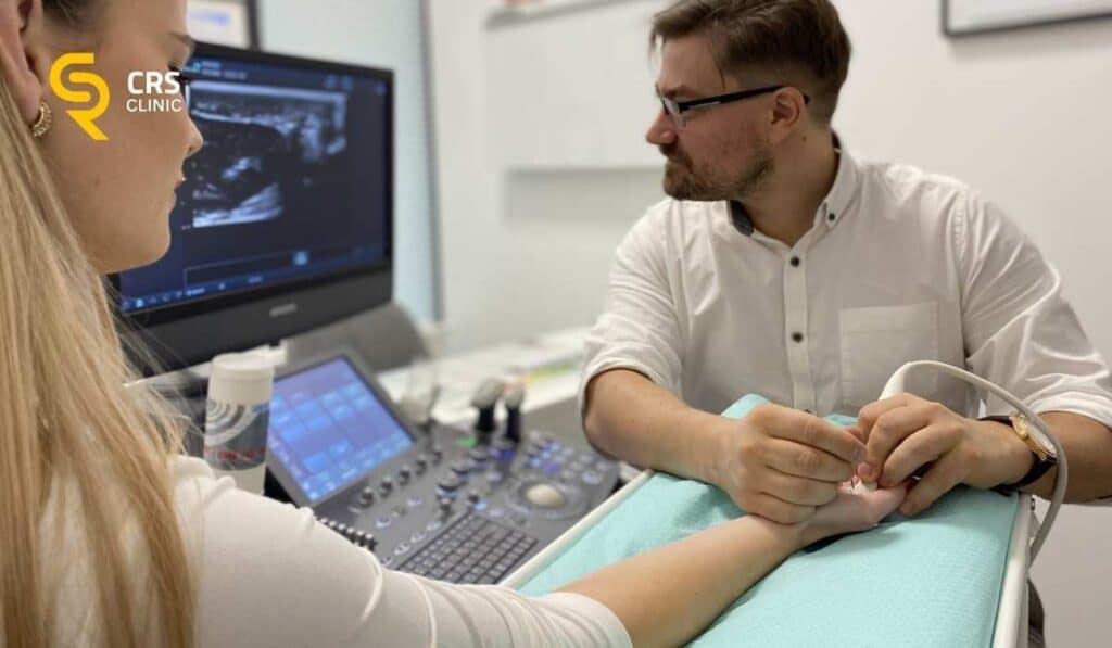 Lekarz ortopeda wykonuje badanie USG ręki u pacjentki z bólem palców w CRS Clinic Warszawa