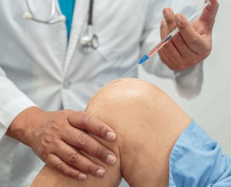 Lekarz wykonuje iniekcje w kolano kwasu hialuronowego