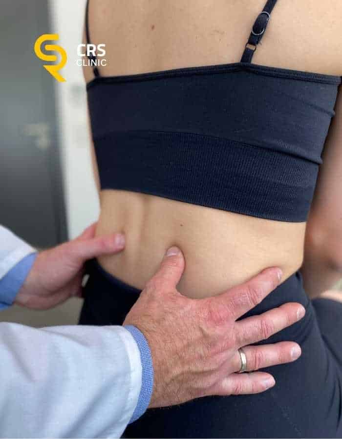 Lekarz neurochirurg wykonuje badanie diagnostyczne i kliniczne u pacjentki z bólem kręgosłupa w CRS Clinic Warszawa