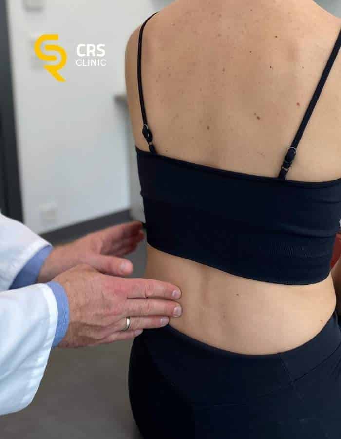 Lekarz ortopeda wykonuje badanie diagnostyczne i kliniczne u pacjentki z bólem kręgosłupa w CRS Clinic Warszawa