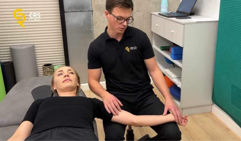 Fizjoterapeuta wykonuje ćwiczenia z pacjentką na ból po zewnętrznej stronie nadgarstka w CRS Clinic Warszawa
