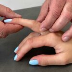 Lekarz ortopeda wykonuje badanie kliniczne w kierunku palca strzelającego