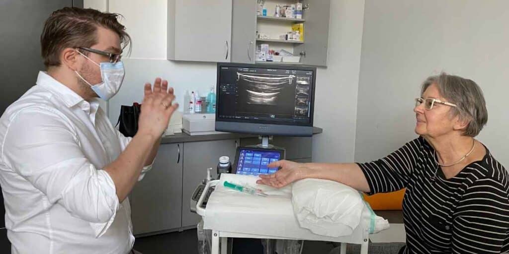 Lekarz ortopeda tłumaczy pacjentce jak wygląda przebieg leczenia cieśni nadgarstka metodą hydrodekompresji w CRS Clinic Warszawa
