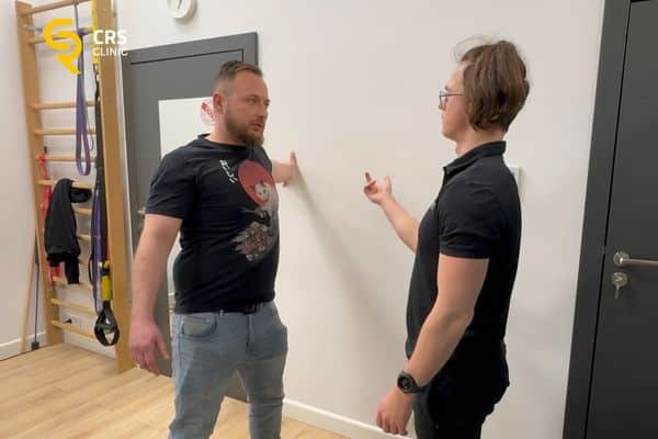 Fizjoterapeuta pracuje z pacjentem i wykonuje ćwiczenia na ból barku w CRS Clinic Warszawa