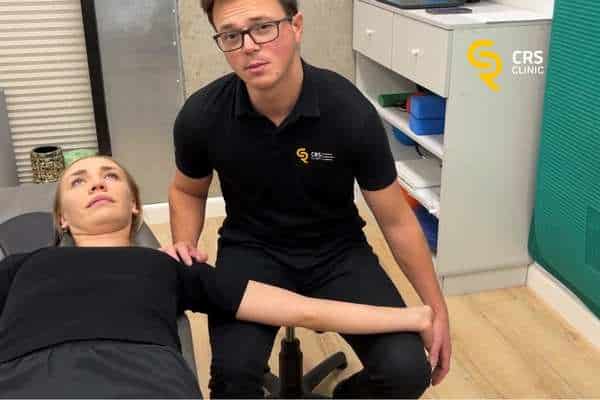 Fizjoterapeuta pracuje z pacjentem i wykonuje neuromobilizację nerwu pośrodkowego cieśni nadgarstka w CRS Clinic Warszawa