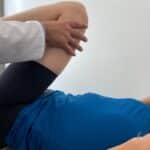 Fizjoterapeuta pracuje z pacjentem z b&oacute;lem biodra i wykonuje ćwiczenia na zwyrodnienie biodra w CRS Clinic Warszawa