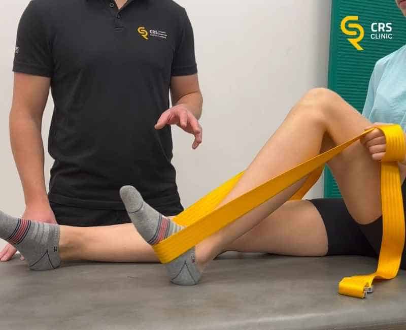 Fizjoterapeuta wykonuje z pacjentem ćwiczenia wzmacniające mięśnie kolana w CRS Clinic Warszawa