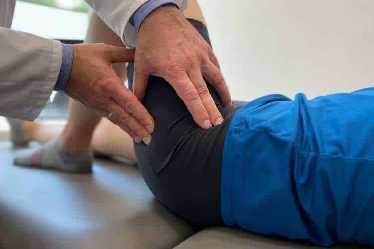 Lekarz ortopeda wykonuje badanie diagnostyczne biodra przy zwyrodnieniu kolana przed leczeniem w CRS Clinic Warszawa