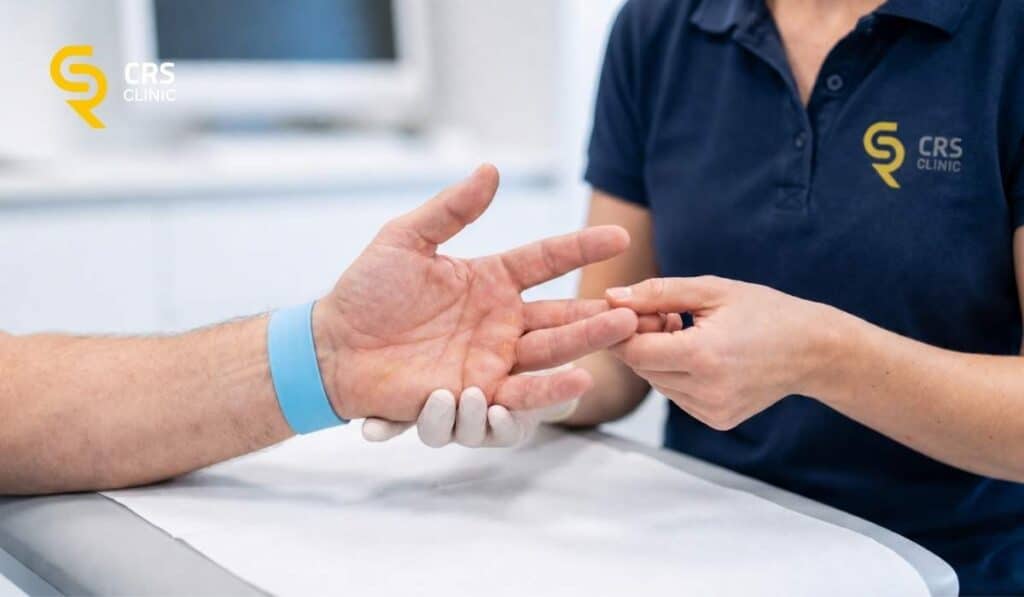 Fizjoterapeuta tłumaczy pacjentowi znaczenie fizjoterapii po zabiegu choroby Dupuytrena w CRS Clinic Warszawa