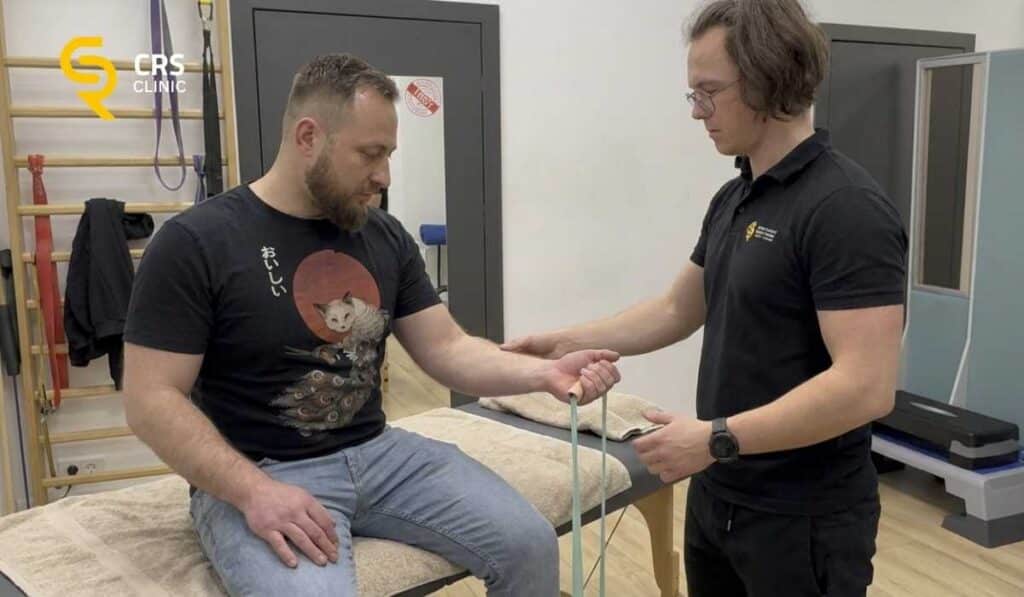 Fizjoterapeuta wykonuje ćwiczenia z pacjętem na wzmocnienie ścięgna przy łokciu golfisty w CRS Clinic Warszawa