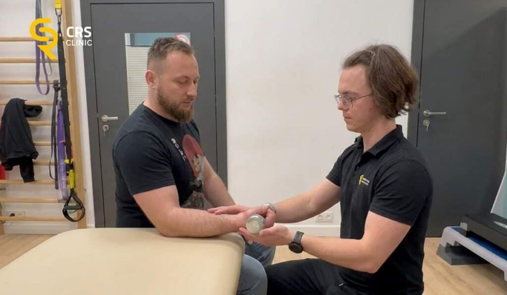 Fizjoterapeuta wykonuje ćwiczenia z pacjętem na wzmocnienie ścięgna przy łokciu tenisisty w CRS Clinic Warszawa
