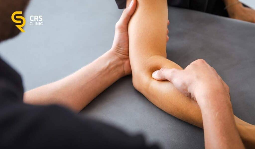 Fizjoterapeuta wykonuje z pacjentem z bólem łokcia ćwiczenia poprawiające funkcjonowanie łokcia w CRS Clinic Warszawa