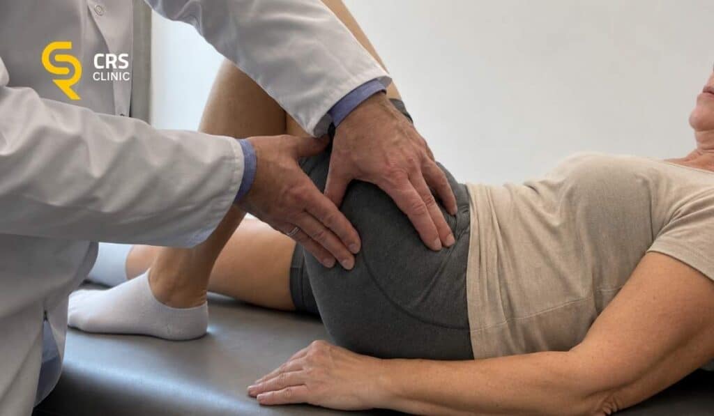 Lekarz ortopeda przeprowadza badanie kliniczne u pacjentki z bólem biodra po zewnętrznej stronie w CRS Clinic Warszawa