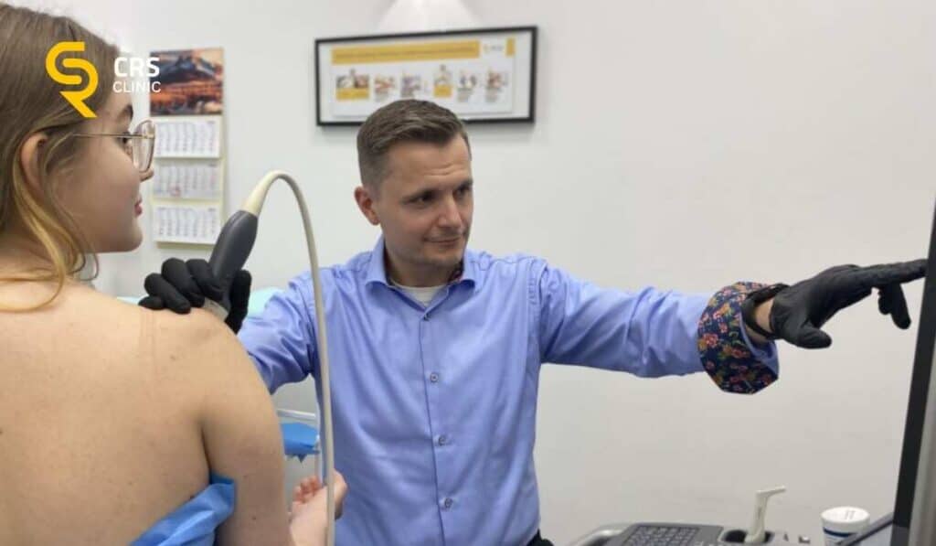 Lekarz ortopeda przeprowadza diagnostykę USG bólu barku u pacjentki w CRS Clinic Warszawa