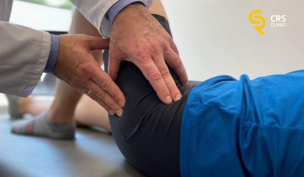 Lekarz ortopeda wykonuje badanie kliniczne biodra u pacjentki z endoprotezą biodra w CRS Clinic Warszawa