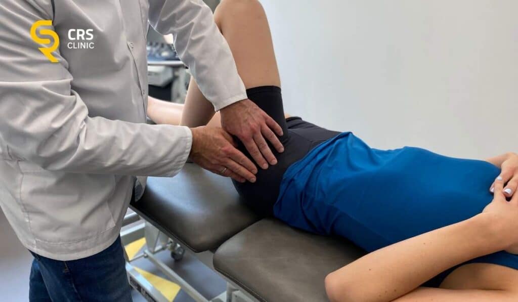 Lekarz ortopeda przeprowadza badanie kliniczne u pacjentki z bólem w pachwinie w CRS Clinic Warszawa