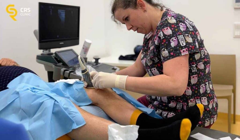 Lekarz ortopeda wykonuje zabieg blokady pod kontrolą USG u pacjenta z bólem kolana w CRS Clinic Warszawa