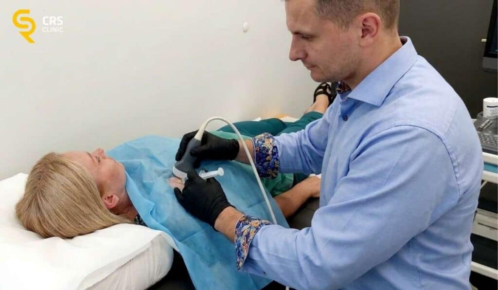 Lekarz ortopeda wykonuje zabieg blokady pod kontrolą USG u pacjentki z bólem barku w CRS Clinic Warszawa