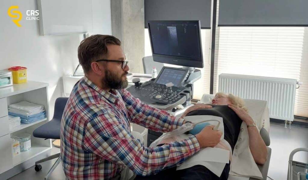 Lekarz ortopeda wykonuje zastrzyk blokady pod kontrolą USG u pacjentki z bólem biodra w CRS Clinic Warszawa