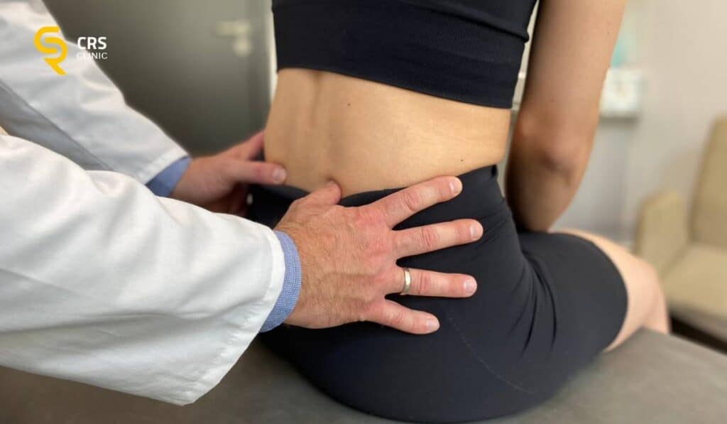 Lekarz ortopeda wykonuje badanie kliniczne kręgosłupa lędźwiowego u pacjentki ze stenozą w CRS Clinic Warszawa