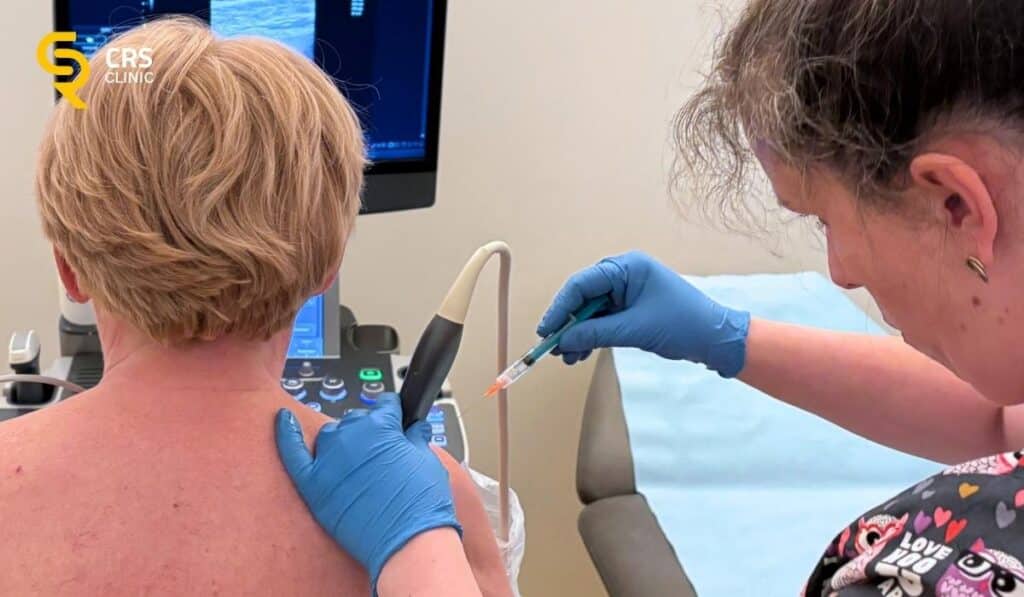 Lekarz ortopeda wykonuje iniekcję sterydową w bark pod kontrolą USG w CRS Clinic Warszawa